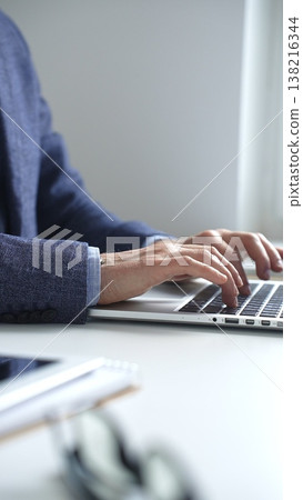 Professional businessman typing on laptop keyboard, working intently while wearing tailored suit and wristwatch in contemporary workspace, vertical close up view. Business people concept Professional businessman typing on laptop keyboard, working intently while wearing tailored suit and wristwatch in contemporary workspace, vertical close up view. Business people concept 138216344