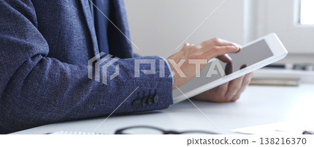Businessman is using a digital tablet to analyze financial data, working with modern technology in the office for strategic corporate decision making and workflow optimization. Business people concept Businessman is using a digital tablet to analyze financial data, working with modern technology in the office for strategic corporate decision making and workflow optimization. Business people concept 138216370