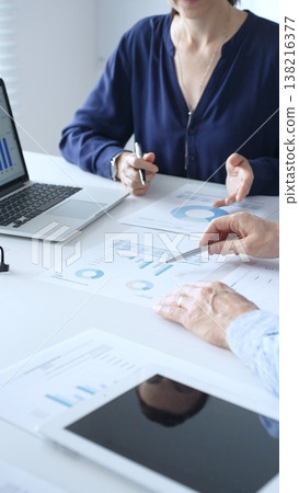 Businessman and businesswoman are analyzing financial data on a laptop and looking through documents, pointing at charts and graphs during a meeting in bright office. Business people concept Businessman and businesswoman are analyzing financial data on a laptop and looking through documents, pointing at charts and graphs during a meeting in bright office. Business people concept 138216377