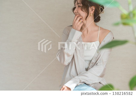 一位衣著時尚的女士站在一面米色牆前。 138216582