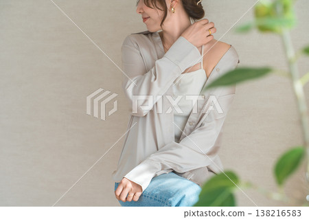 A stylish woman standing in front of a beige wall. A stylish woman standing in front of a beige wall. 138216583