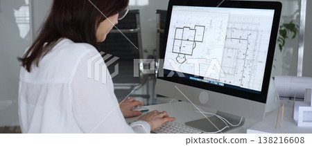 Woman architect drawing building plans on computer, designing modern housing project with cad software. Business and architecture concept Woman architect drawing building plans on computer, designing modern housing project with cad software. Business and architecture concept 138216608