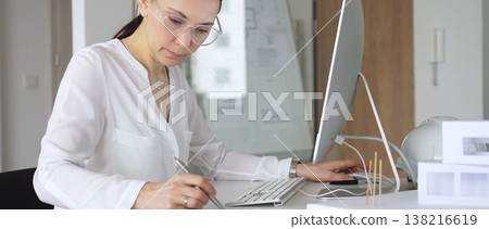 Woman architect sketching, designing, and brainstorming new building structure concepts in a modern office using computer technology. Business and architecture concept 138216619
