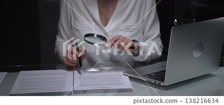 Woman analyzing contract text with magnifying glass, scrutinizing fine print for legal details and agreement review. Audit, business and overworking concepts Woman analyzing contract text with magnifying glass, scrutinizing fine print for legal details and agreement review. Audit, business and overworking concepts 138216634