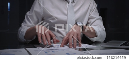 Business professional analyzing financial data with charts and reports on desk, working late in dark office. Audit and overworking concepts Business professional analyzing financial data with charts and reports on desk, working late in dark office. Audit and overworking concepts 138216659