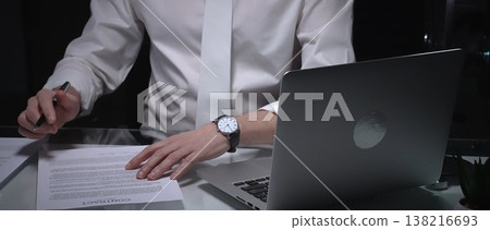 Business man signing a contract late in the office, closing a deal, or completing legal paperwork at deep night. Audit and overworking concepts 138216693
