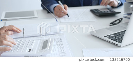Close up of female accountant hands using calculator while collaborating with male colleague in office, calculating taxes and analyzing financial data. Audit and taxes in business Close up of female accountant hands using calculator while collaborating with male colleague in office, calculating taxes and analyzing financial data. Audit and taxes in business 138216700