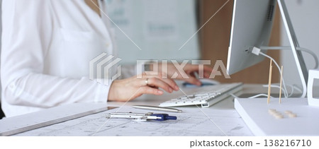 Architect woman working on blueprint design and computer in modern office, using specialized tools for urban planning project. Business and architecture concept 138216710
