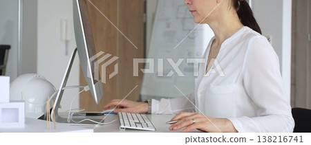 Woman architect working on desktop computer, typing and designing building plans in modern office. Business and architecture concept 138216741