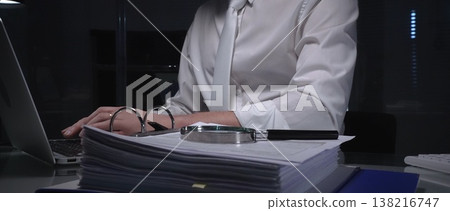 Businessman analyzing financial documents and paperwork at desk, working overtime in a dark office, researching data for investigation. Audit and taxes in business Businessman analyzing financial documents and paperwork at desk, working overtime in a dark office, researching data for investigation. Audit and taxes in business 138216747