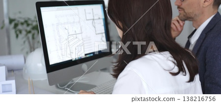 Architects collaborating on building plans using computer aided design software and architectural models. Business and architecture concept Architects collaborating on building plans using computer aided design software and architectural models. Business and architecture concept 138216756