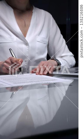 Businesswoman signing a contract late in the office, closing a deal, or completing legal paperwork at deep night. Audit and overworking concepts Businesswoman signing a contract late in the office, closing a deal, or completing legal paperwork at deep night. Audit and overworking concepts 138216886