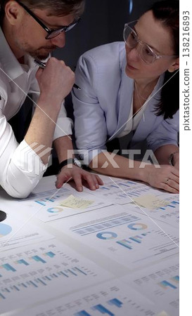 Business colleagues collaborating on financial reports, analyzing market data and corporate strategy by reviewing charts and graphs on a table in an office meeting Business colleagues collaborating on financial reports, analyzing market data and corporate strategy by reviewing charts and graphs on a table in an office meeting 138216893