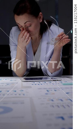 Stressed business woman suffering from headache in dark office, hands on head experiencing burnout and fatigue during late night work, facing deadline pressure and financial difficulties Stressed business woman suffering from headache in dark office, hands on head experiencing burnout and fatigue during late night work, facing deadline pressure and financial difficulties 138217004