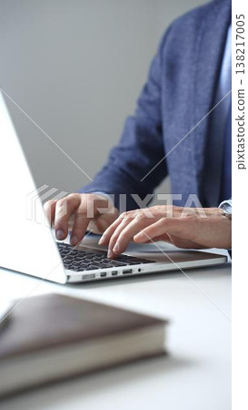 Close up of businessman's hands typing on laptop keyboard, working diligently in a modern office setting, wearing a suit and watch. Business people concept Close up of businessman's hands typing on laptop keyboard, working diligently in a modern office setting, wearing a suit and watch. Business people concept 138217005