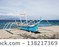 Traditional outrigger fishing boat on sandy shore by deep blue ocean 138217369