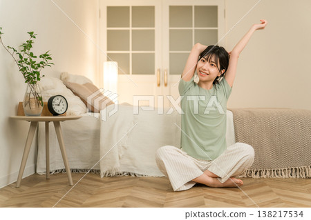 一位年輕的亞洲女性在夜間於臥室裡做伸展和柔軟度練習。 一位年輕的亞洲女性在夜間於臥室裡做伸展和柔軟度練習。 138217534