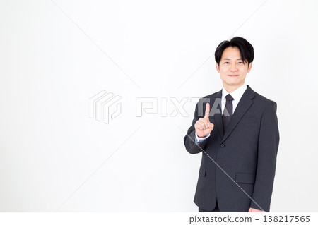 A middle-aged businessman holding up his index finger. 138217565