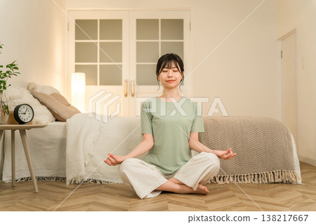 一位年輕的亞洲女性晚上在臥室裡做瑜伽和冥想。 一位年輕的亞洲女性晚上在臥室裡做瑜伽和冥想。 138217667