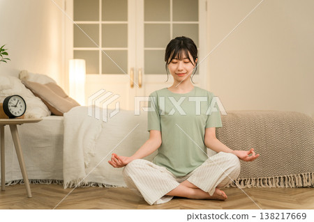 A young Asian woman doing yoga and meditation in her bedroom at night. 138217669