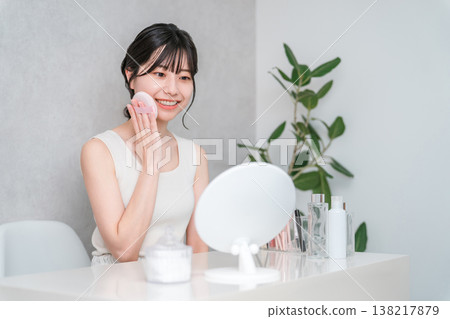 Smiling Asian woman applying foundation powder makeup 138217879