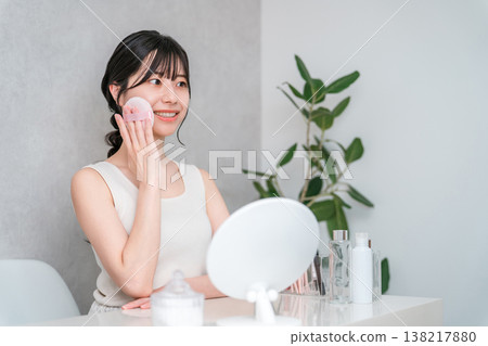 Smiling Asian woman applying foundation powder makeup 138217880
