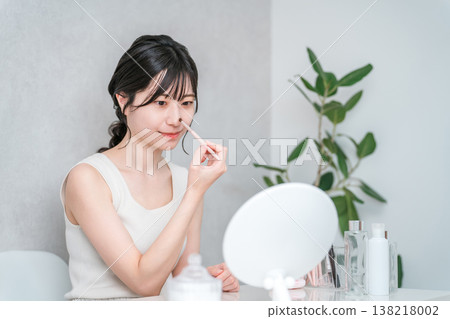 一位女士正在用化妝刷塗抹鼻影和高光等化妝品。 138218002