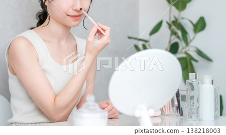 一位女士正在用化妝刷塗抹鼻影和高光等化妝品。 138218003