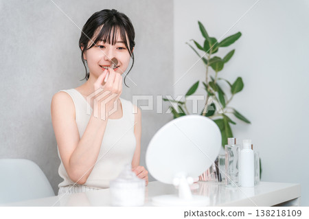 Asian woman applying makeup with cheek brush and face brush Asian woman applying makeup with cheek brush and face brush 138218109
