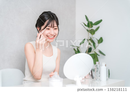 年輕的亞洲女性在化妝時塗抹眼影 年輕的亞洲女性在化妝時塗抹眼影 138218111