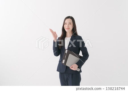 一位微笑的女商人手裡拿著文件,引導客戶。 一位微笑的女商人手裡拿著文件,引導客戶。 138218744