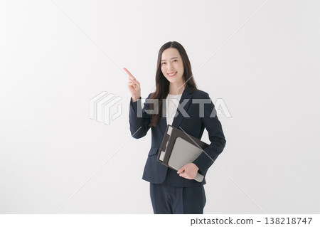 A smiling businesswoman guides a client with a file in her hand. 138218747