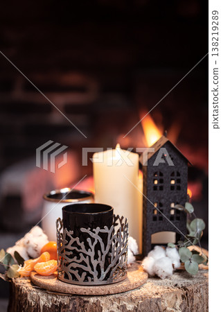 Cozy composition with a cup, candle and tangerines on a blurred background. 138219289