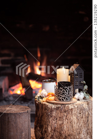 Cozy composition with a cup, candle and tangerines on a stump near the fireplace copy space. Cozy composition with a cup, candle and tangerines on a stump near the fireplace copy space. 138219290