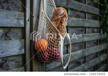 String bag with bread and fruits on a wooden background. String bag with bread and fruits on a wooden background. 138219305