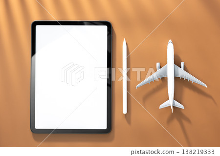 Tablet and airplane miniature on brown background, top view, copy space. Tablet and airplane miniature on brown background, top view, copy space. 138219333