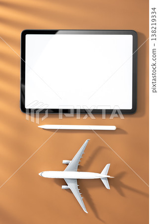 Tablet and airplane miniature on brown background, top view, copy space. Tablet and airplane miniature on brown background, top view, copy space. 138219334