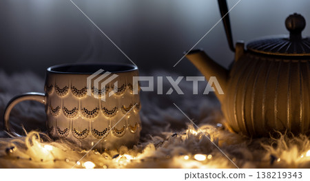 Teapot and cup on a blurred background in the dark with garlands. Teapot and cup on a blurred background in the dark with garlands. 138219343