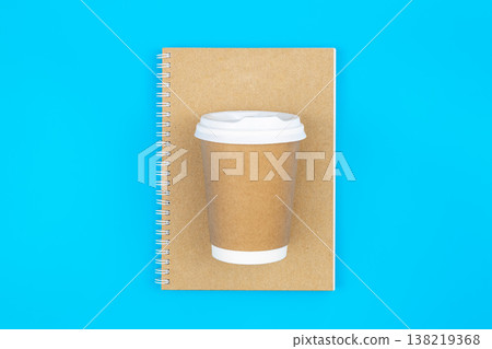 Top view of closed spiral blank recycled paper cover notebook with paper cup. Top view of closed spiral blank recycled paper cover notebook with paper cup. 138219368