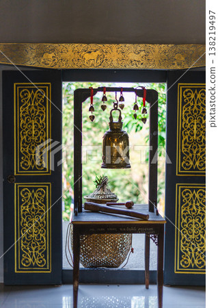 Traditional Thai temple bell framed by ornate doorway with wooden striker and decorative patterns Traditional Thai temple bell framed by ornate doorway with wooden striker and decorative patterns 138219497