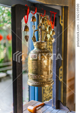 Traditional Buddhist temple bell with wooden striker and hanging small bells inside Thai shrine interior Traditional Buddhist temple bell with wooden striker and hanging small bells inside Thai shrine interior 138219500