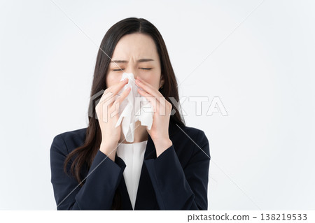A woman with hay fever wipes her runny nose with a tissue. A woman with hay fever wipes her runny nose with a tissue. 138219533