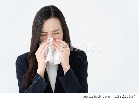 A woman with hay fever wipes her runny nose with a tissue. A woman with hay fever wipes her runny nose with a tissue. 138219534