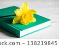 Yellow flower and book on a blurred white background, close-up. 138219845
