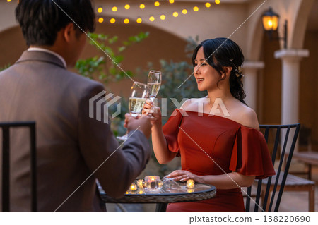 一對新人穿著晚宴婚禮禮服，在晚餐時喝香檳。 138220690