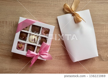 Delicious, sweet handmade chocolates made of white and milk chocolate with whole nuts in a gift box on a light background 138221069