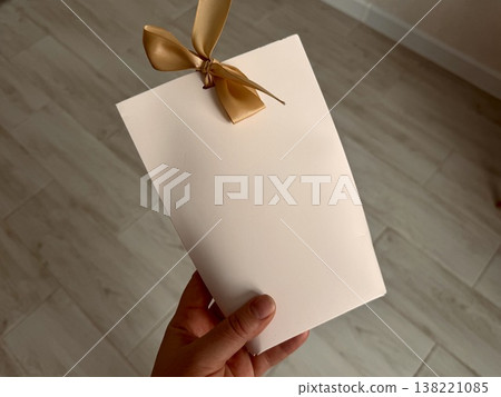 White gift wrap tied with a beige bow on top on a neutral background White gift wrap tied with a beige bow on top on a neutral background 138221085