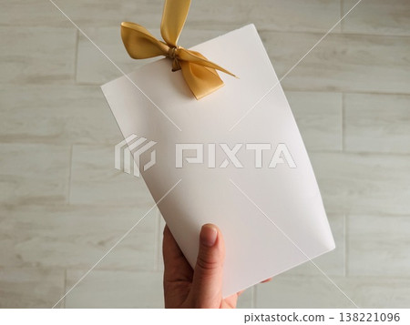 White gift wrap tied with a beige bow on top on a neutral background White gift wrap tied with a beige bow on top on a neutral background 138221096