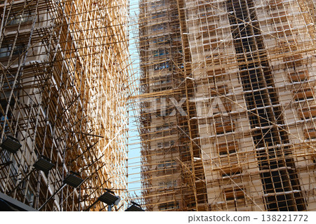 Bamboo scaffolding covering building under construction against blue sky 138221772