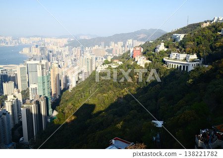 Daytime aerial view of Hong Kong island skyscrapers and hillside greenery from Victoria Peak observation deck 138221782